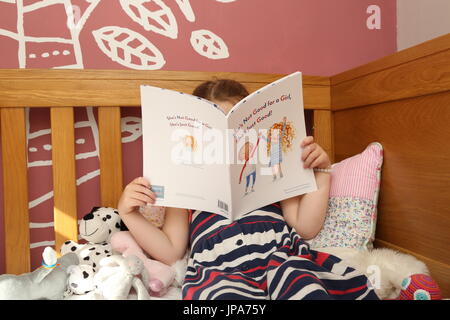 Ein junges Mädchen sitzt auf ihrem Bett und liest ein Buch der neuen Kinderautorin Suzanne Hemming. Gesicht ausgeblendet Stockfoto