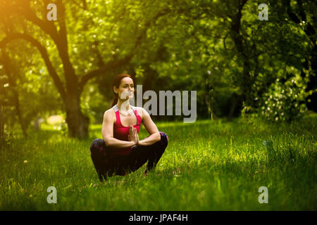Frau praktizieren Yoga konzentriert sich in Girlande-Pose. Stockfoto