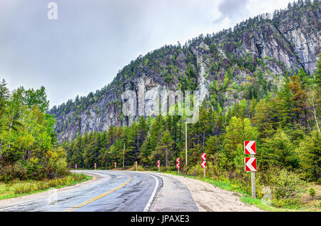 Autobahn-Straße in stürmischen nebligen und nebligen Wetter in Charlevoix Bergregion von Quebec, Kanada mit abbiegen Stockfoto