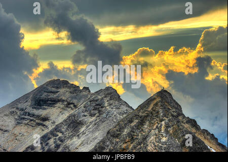 Bergsteiger steht am Gipfel im Abendlicht Stockfoto