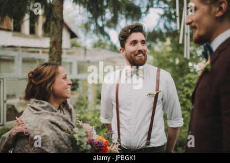 Alternative Hochzeit, Braut und Bräutigam im Gespräch mit einem Freund Stockfoto