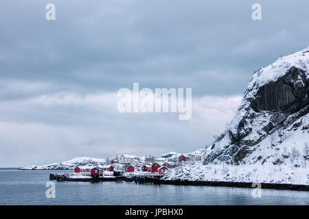 Kalte Meer und schneebedeckten Gipfeln Frame das Fischerdorf in der Dämmerung Nusfjord Lofoten Nordland Nordnorwegen Europa Stockfoto