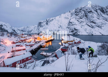 Fotografen in der Abenddämmerung in der Nähe des Fischerdorfes beschneit Nusfjord Nordland Lofoten Inseln Norwegen Nordeuropa Stockfoto