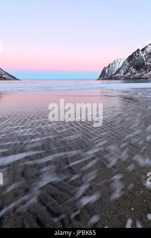Die rosa Licht des Sonnenaufgangs Frames die Wellen der gefrorene Meer von schneebedeckten Gipfeln Ersfjord Senja Tromsø Norwegen Europa umgeben Stockfoto