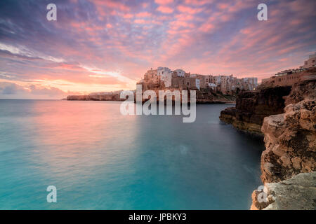 Rosa Sonnenaufgang auf das türkisfarbene Meer, eingerahmt von Altstadt thront auf den Felsen Polignano eine Stute Provinz von Bari Apulien Italien Europa Stockfoto