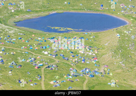 Camping und Zelten in grünen Wiesen umgeben von einem blauen See Vaeroy Insel Nordland Grafschaft Lofoten Inselgruppe Norwegen Europa Stockfoto