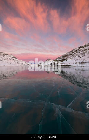 Die gefrorenen Lago Bianco umrahmt von rosa Wolken im Morgengrauen Berninapass Kanton Graubünden-Engadin-Schweiz-Europa Stockfoto