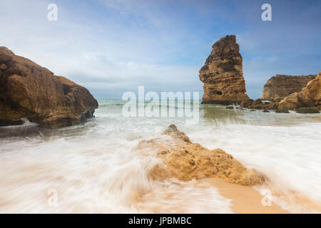 Wellen, die am Sandstrand umgeben von Klippen Praia da Marinha Caramujeira Lagoa Gemeinde Algarve Portugal Europa Stockfoto