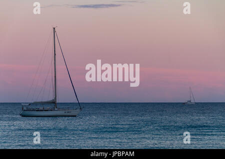 Zwei Segelboote Segeln auf das ruhige Meer in der Nähe der Südküste von Sardinien bei Sonnenuntergang. Mittelmeer, Italien Stockfoto