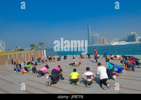 HONG KONG, CHINA - 26. Januar 2017: Masse der Leute, die Ausübung von Tai Chi am Vormittag mit einem Downton der Stadt von Hong Kong als Hintergrund. Ein Land von 1.104 km mit 7 Millionen Einwohnern ist Hong Kong eine der am dichtesten besiedelten Gebiete der Welt Stockfoto