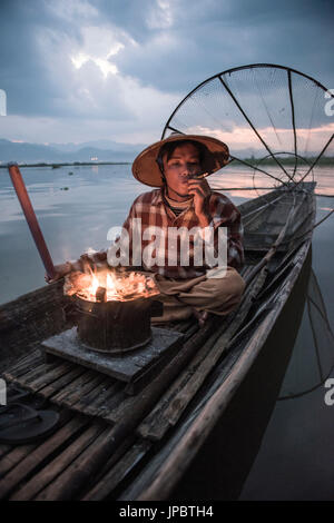 Inle-See, Nyaungshwe Township Taunggyi Bezirk, Myanmar (Burma). Lokale Fischer vor der Morgendämmerung mit Kamin auf dem Boot. Stockfoto