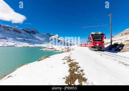 Bernina-Express-Zug im verschneiten Tal umgeben von See Bianco Bernina Pass Kanton Graubünden Engadin Schweiz Europa Stockfoto