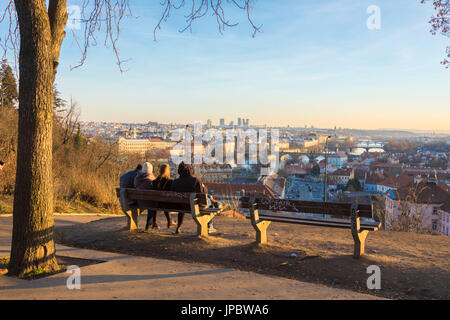Menschen auf einer Bank zu bewundern, die historischen Gebäude und Brücken am Fluss Vltava (Moldau) bei Sonnenuntergang Prag Tschechische Republik Europa Stockfoto