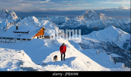 Wanderer mit Schäferhund auf dem verschneiten Kamm, umgeben von den hohen Gipfel des Monte Civetta Dolomiten Belluno Provinz Venetien Italien Europa Stockfoto