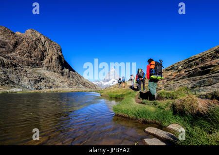 Wanderer gehen auf die Ufer des Sees Riffelsee mit Matterhorn im Hintergrund Zermatt Kanton Wallis Schweiz Europa Stockfoto