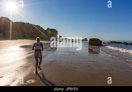 Sonnenstrahlen auf einen Läufer auf dem feinen Sandstrand gebadet durch den Ozean Praia da Rocha Portimao Faro Bezirk Algarve Portugal Europa Stockfoto