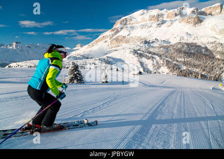 Blauer Himmel und Sonne umrahmen die Skifahrer auf den verschneiten Skipisten von Cherz Arabba Dolomiten Venetien Italien Europa Stockfoto