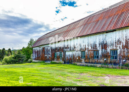 Eine große hölzerne Scheune mit roten Metalldach als Residenz (falls
