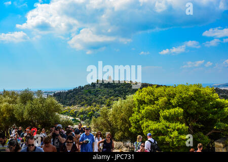 Touristen in alten Ruinen Athens mit dem Philopappos Denkmal auf Mouseion Hill im Hintergrund an einem sonnigen Tag Stockfoto