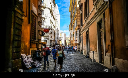 Eine junge Frau und zwei junge Männer, die zu Fuß in einer schattigen Gasse in der historischen Centery von Rom Italien an einem Sommernachmittag Stockfoto