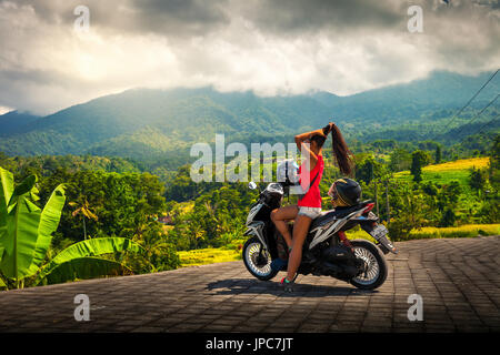 Young Travel Mädchen touristische erforschen tropische Insel Bali mit dem Fahrrad und einer atemberaubenden Aussicht natur berge Landschaft im Nebel Wolken genießen. Travel Concept Stockfoto