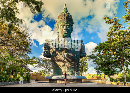 Junge schöne Frau Reisenden genießen Sie spektakuläre Aussicht traditionelle hinduistische Architektur im Garuda Wisnu Kencana Cultural Park, Bali, Indonesien Stockfoto