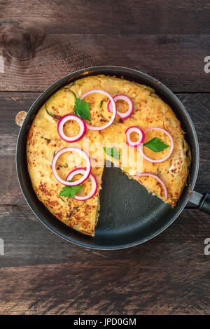 Eine obenliegende Foto eine spanische Tortilla mit Kartoffeln und Zucchini in eine Tortillera mit einer fehlenden Scheibe und einen Platz für text Stockfoto