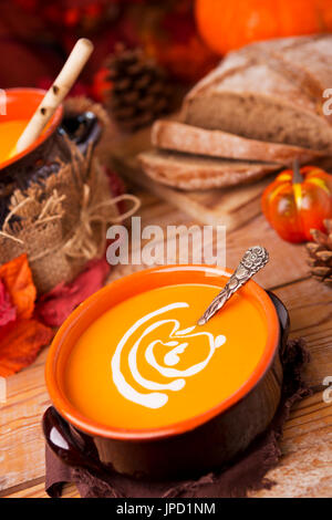 Eine Schüssel mit hausgemachte cremige Kürbissuppe auf einem rustikalen Tisch mit herbstlichen Dekorationen. Stockfoto