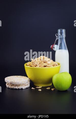 Energiefrühstück für Ernährung Getreideflocken Mais Milch und grüner Apfel auf schwarzem Hintergrund mit Textfreiraum Stockfoto