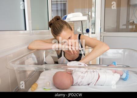 Frau spielt mit Baby in der Wiege Stockfoto