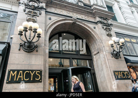 Die Frau ist, die von einem Eingang zu der des Macys Department Store in Manhattan. Stockfoto