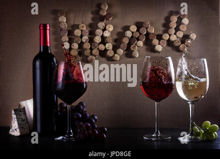 Weinkonzept Flasche und Gläser mit roten, rosa und weißen Spritzer Wein am Tisch mit Wort Wein geschrieben in Korken Stockfoto