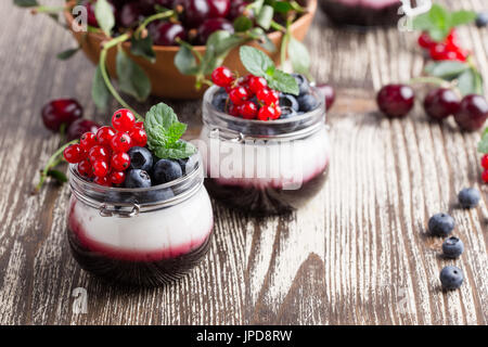 Sommer-Joghurt-Dessert mit Sauerkirschen, rote Johannisbeeren und Heidelbeeren Gelee und dekoriert mit frischen Beeren Stockfoto