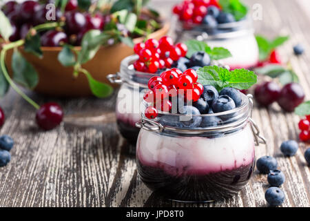 Sommer-Joghurt-Dessert mit Sauerkirschen, rote Johannisbeeren und Heidelbeeren Gelee und dekoriert mit frischen Beeren Stockfoto