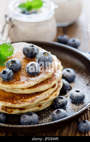 Gesunde Bio Heidelbeer-Smoothie in Glas und Buttermilch Pfannkuchen mit frischen Beeren auf rustikalen Holztisch Stockfoto