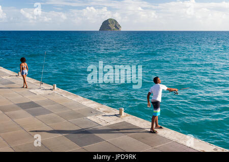 Junge Fischer auf Le Diamant Pier in Martinique mit Diamond Rock im Hintergrund Stockfoto