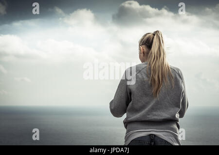 Blonde junge lächelnde Frau Porträt mit mit unscharfen Berge Landschaft auf dem Hintergrund im bewölkten Tag Stockfoto