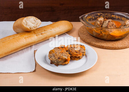 Frikadelle aus Schweinefleisch serviert auf einem weißen Teller und weiße Weizenbrot. Hausgemachte Frikadellen gebraten mit Gemüse in Keramikschale, klassisches Rezept. Zusammensetzung Stockfoto