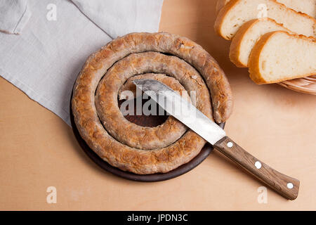 Geröstete traditionelle hausgemachte Wurst mit Gewürzen und Kräutern auf braunen Ton Platte. Scheiben weiße Weizenbrot in gelb aus Holz Korb. Traditionelle Ukraine Stockfoto