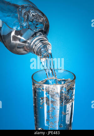 Wasser in Glas gießen, über blauem Hintergrund Stockfoto