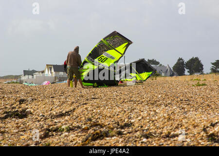 Ein paar junge Männer Kampf gegen eine steife Brise, bereiten Sie ihre Para-Gleiter für einen Nachmittag Sport am Strand in Titchfield Hampshire in th Stockfoto