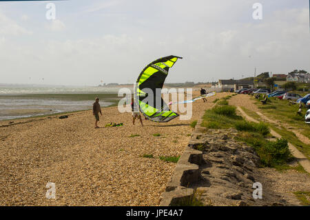 Ein paar junge Männer Kampf gegen eine steife Brise, bereiten Sie ihre Para-Gleiter für einen Nachmittag Sport am Strand in Titchfield Hampshire in th Stockfoto