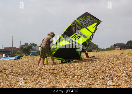 Ein paar junge Männer Kampf gegen eine steife Brise, bereiten Sie ihre Para-Gleiter für einen Nachmittag Sport am Strand in Titchfield Hampshire in th Stockfoto