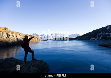 Europa, Italien, Südtirol, Trient, Val Nambrone Tal, Brenta Dolomiten, cornisello Seen. Der Lago Nero See und Cima Tosa Alp mit Wanderer Silhouette im Winter. Stockfoto