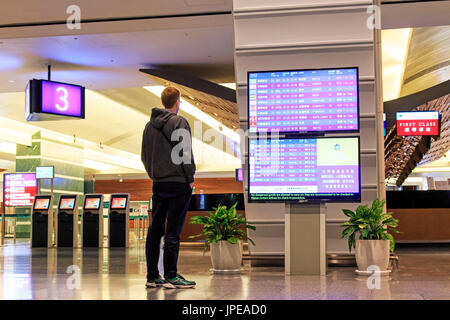 Taipei, Taiwan. Mann Stading vor einem Flug Information Board innerhalb des Taiwan Taoyuan International Airport, dem verkehrsreichsten Flughafen im Land und die wichtigsten internationalen Drehscheibe für China Airlines und EVA Air. Stockfoto