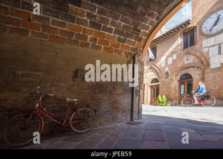 Blick auf das historische Zentrum von Buonconvento mit Übergang von einem Radfahrer. Buonconvento, Ombronetal, Crete senesi, Provinz Siena, Toskana, Italien, Europa Stockfoto