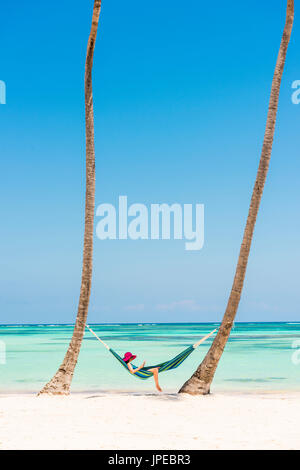 Juanillo Strand (Playa Juanillo), Punta Cana, Dominikanische Republik. Entspannen Sie sich auf einer Hängematte an einem palmengesäumten Strand (MR) Frau. Stockfoto