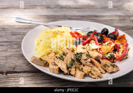 Spicy Chicken Diablo mit Koriander, Oliven, Paprika, Knoblauch und Zwiebeln auf gelber Safranreis serviert. Stockfoto