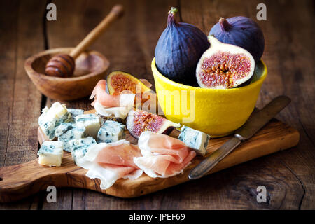 Italienische Vorspeise oder Fleisch- und Käseplatte mit frischen Feigen, Serrano-Schinken Schinken und würzigem Gorgonzolakäse dunklen hölzernen Hintergrund Stockfoto