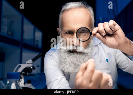 Porträt des fokussierten Wissenschaftlers Blick zur hand durch Lupe im Labor Stockfoto